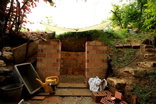 Mauern im Trocknen trotz Regenwetter. Das Tarp leistet gute Dienste, und wird zum "Baustellengegenstand des Monats" gekürt.