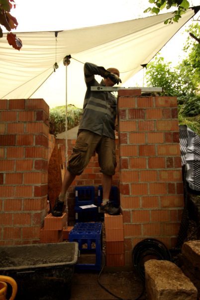 Doch bevor wir die Rundbögen mauern, haben wir noch einen Arbeitsschritt: die 14. und letzte Mauerreihe. Nachdem wir nochmal Mauerhöhe / Stich (= Grad der Wölbung) / Endhöhe Erdkeller hin- und hergerechnet haben, stand fest, dass wir dafür die alten halbhohen Ziegel, die wir aus´m Dorf geholt haben, nehmen.